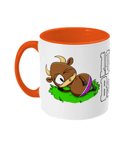 Load image into Gallery viewer, A brown bull with big horns reclining on a patch of grass wearing pink briefs.
